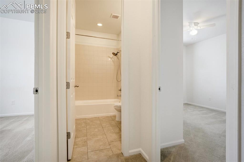 Image 31 of 36: Bathroom with a ceiling fan, shower / washtub combination, and tile pattern