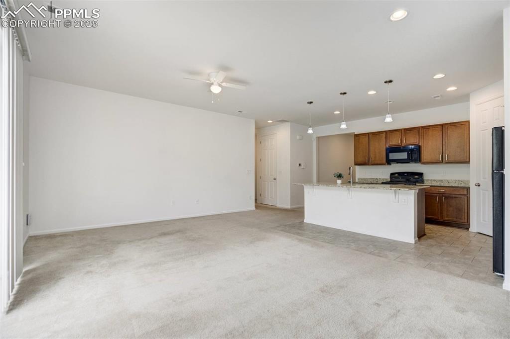 Image 8 of 36: Kitchen with black microwave, open floor plan, ceiling fan, light carpet, a