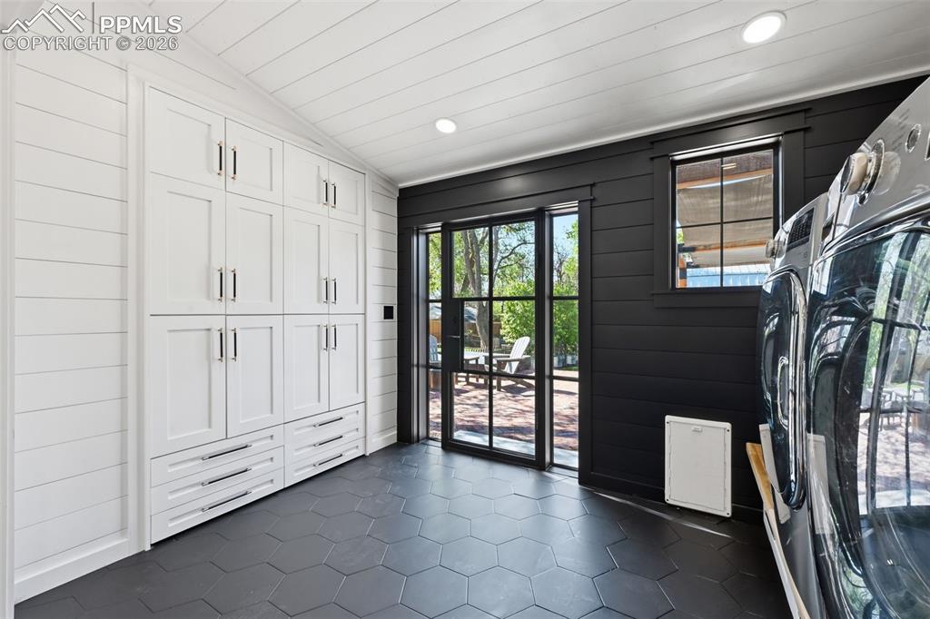 Image 15 of 50: The laundry space is complete with a stunning metal rear door, convenient d
