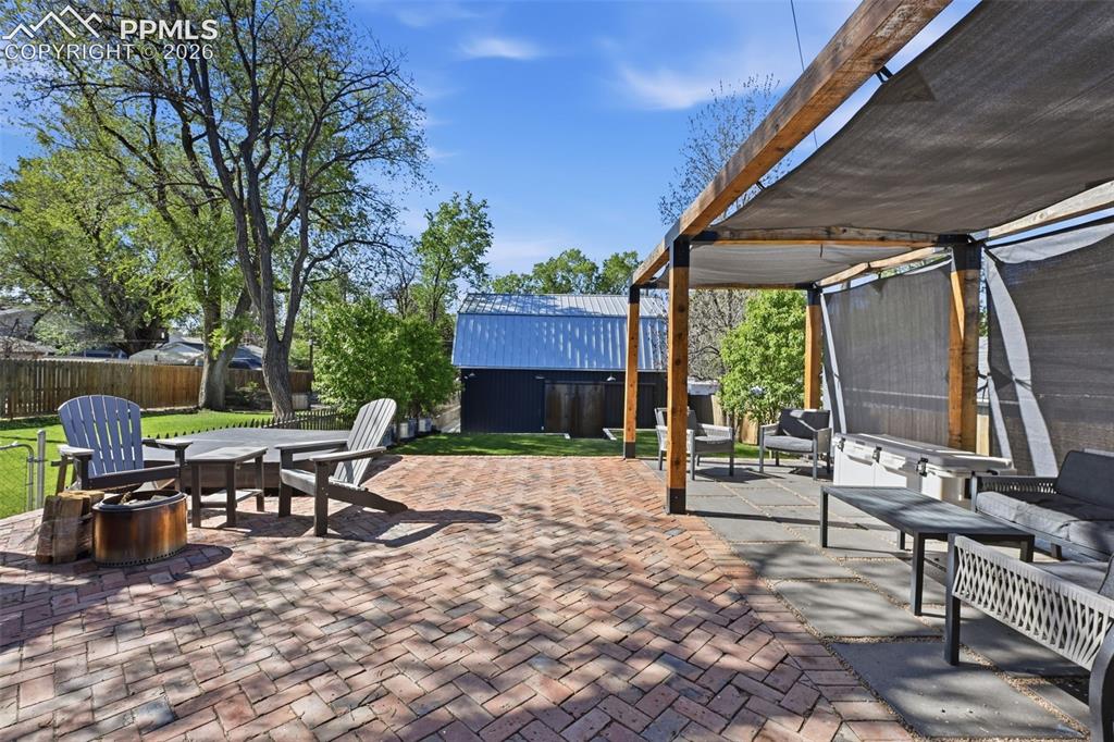 Image 24 of 50: Covered pergola is complete with a brick and paver porch, and room for a fi