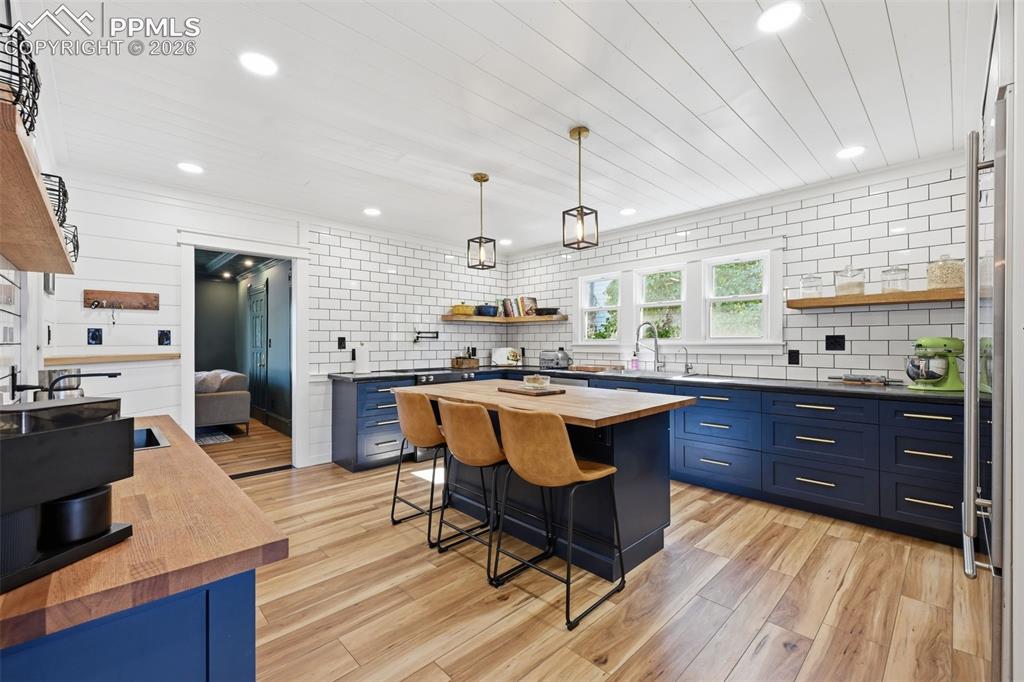 Image 8 of 50: Beautifully remodeled kitchen hosts bold cabinets, soothing LVP floors, and