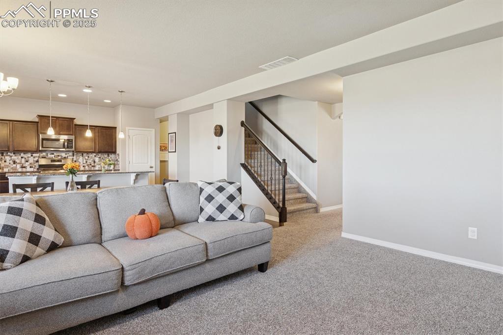 Image 17 of 45: Living area with recessed lighting, light carpet, and stairs