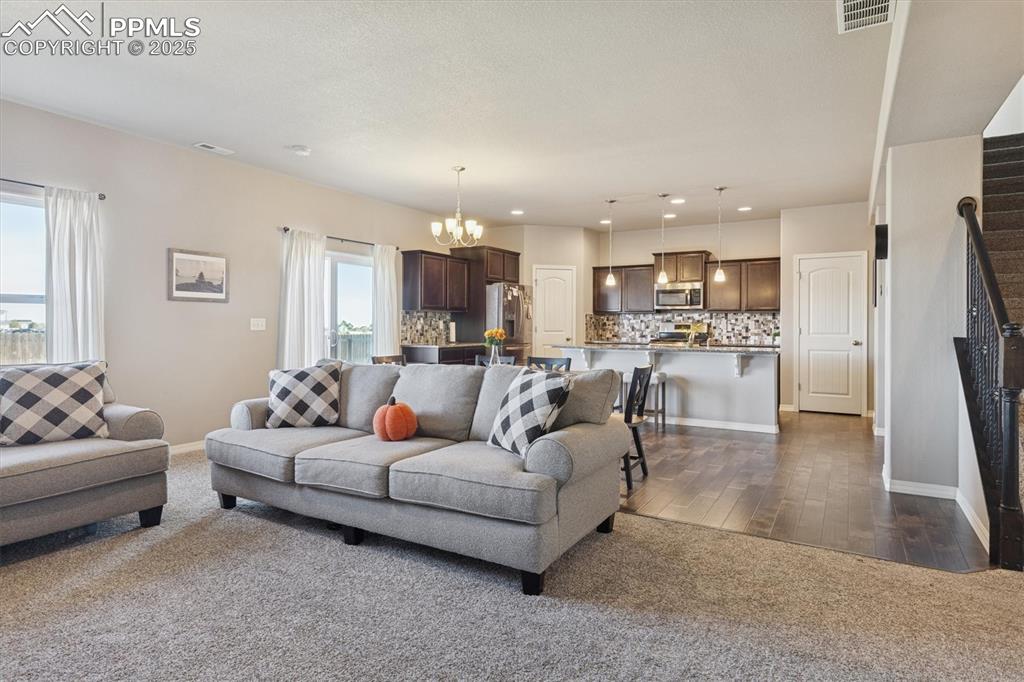 Image 18 of 45: Living room featuring a chandelier, dark carpet, recessed lighting, stairwa