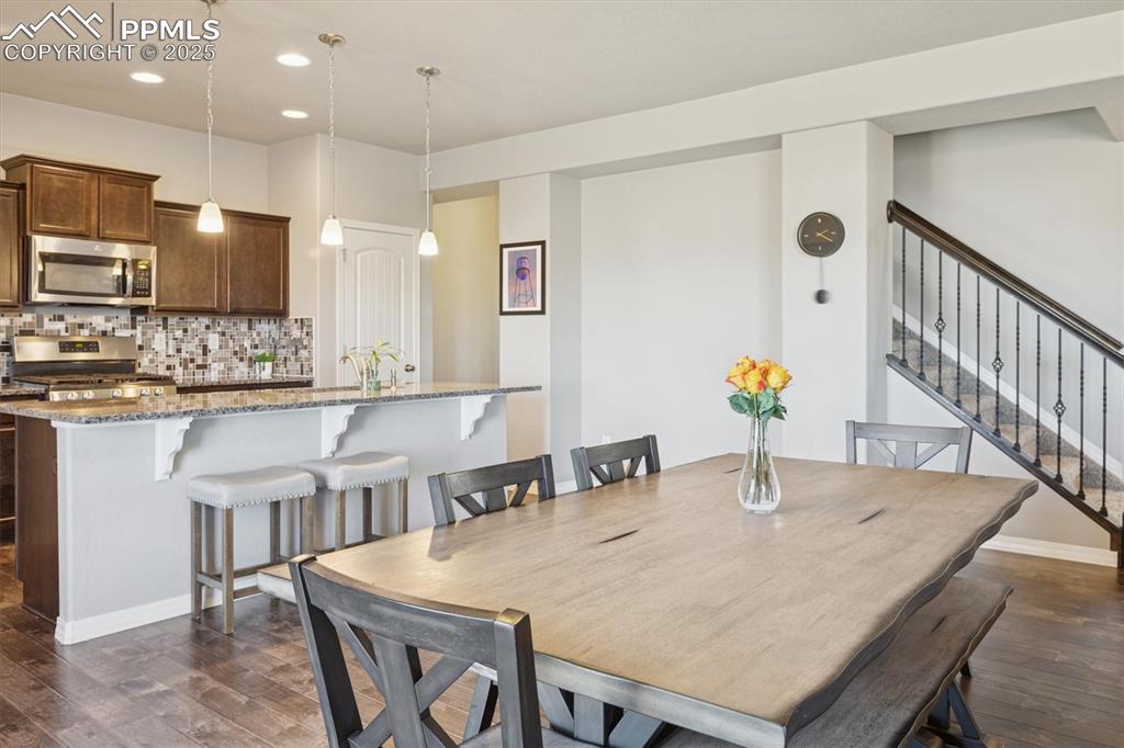 Image 20 of 45: Dining space featuring dark wood-type flooring, stairs, and recessed lighti