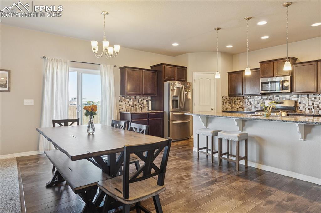 Image 21 of 45: Dining space featuring a chandelier, dark wood-type flooring, and recessed