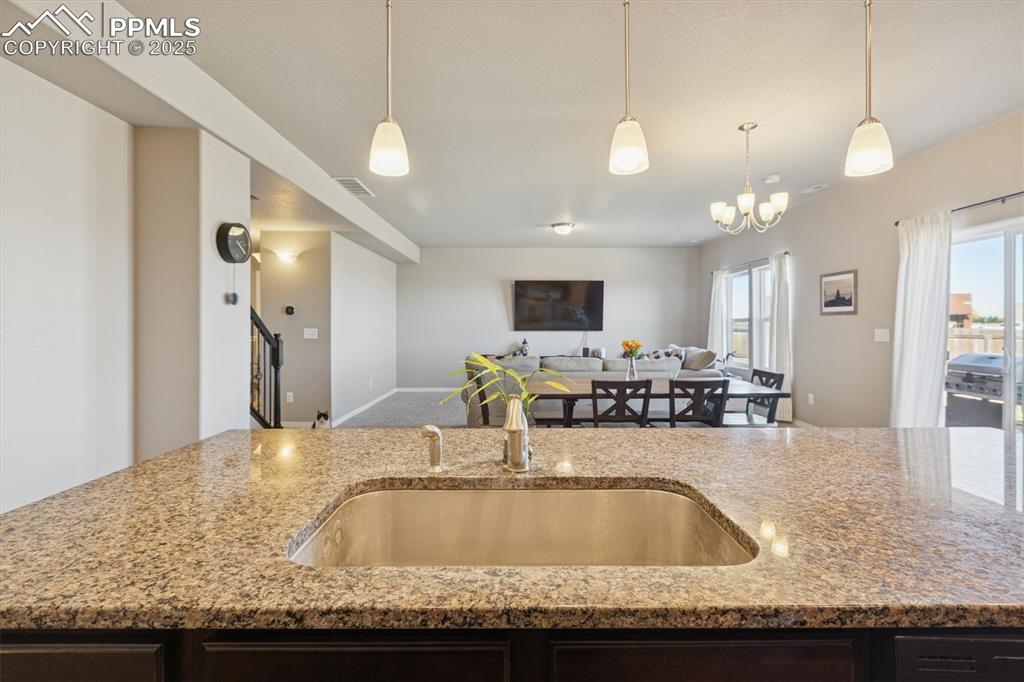 Image 24 of 45: Kitchen featuring dark brown cabinets, light stone countertops, and decorat