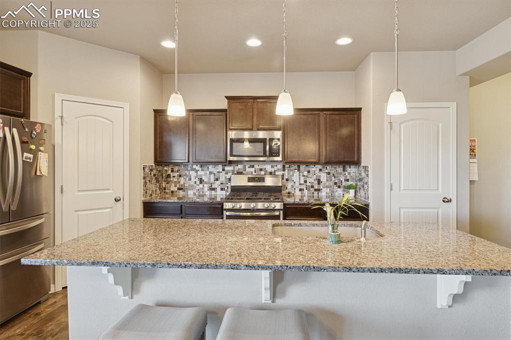 Image 26 of 45: Kitchen with appliances with stainless steel finishes, light stone countert
