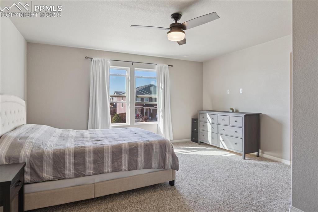 Image 28 of 45: Carpeted bedroom with a ceiling fan and baseboards