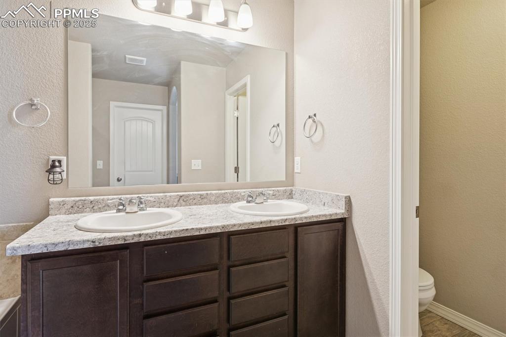 Image 32 of 45: Bathroom with a textured wall and double vanity