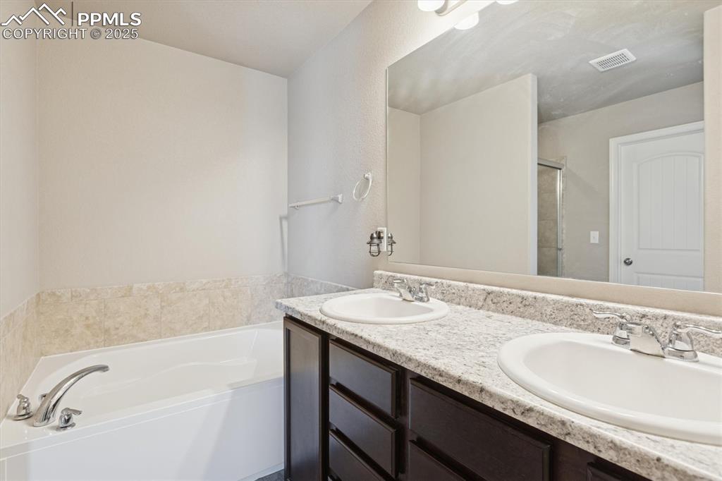 Image 33 of 45: Full bath with a bath, double vanity, and a stall shower