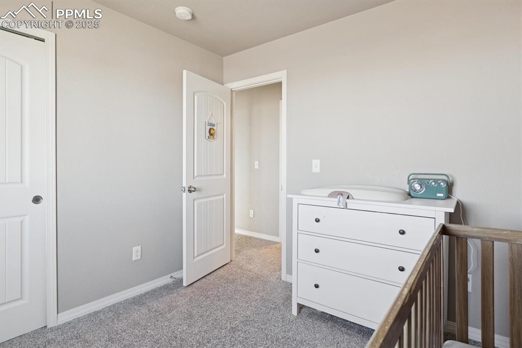 Image 35 of 45: Bedroom with light carpet and a nursery area