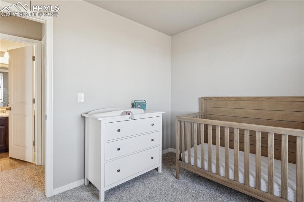 Image 36 of 45: Bedroom with light colored carpet and a nursery area