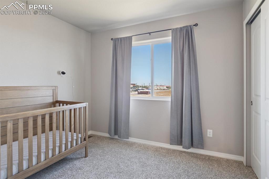 Image 37 of 45: Bedroom with light colored carpet, a nursery area, and a closet