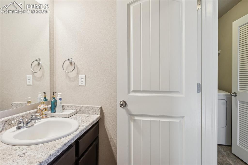 Image 39 of 45: Bathroom featuring washer / dryer, vanity, a textured wall, and dark wood-s