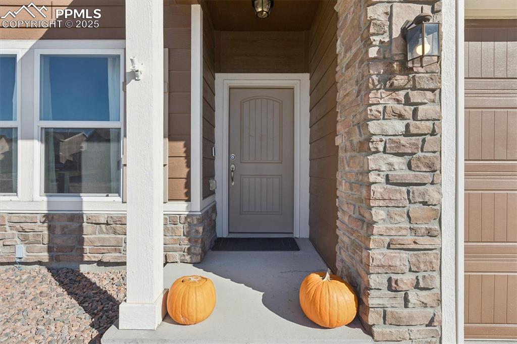 Image 6 of 45: Entrance to property featuring stone siding and a porch