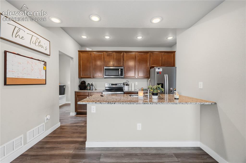Image 12 of 45: The Island Kitchen features recessed lighting, a breakfast bar, wood cabine
