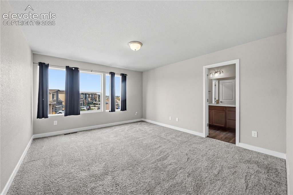 Image 18 of 45: Spacious upper level Primary Retreat with neutral carpet, a wall of windows