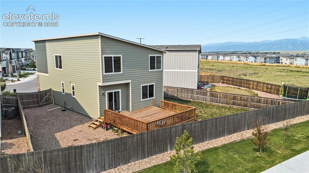 Image 33 of 45: Fenced, xeriscaped backyard with wood deck and mountain views.
