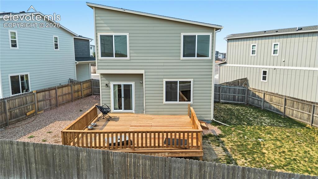 Image 34 of 45: Rear view of home and fenced backyard.