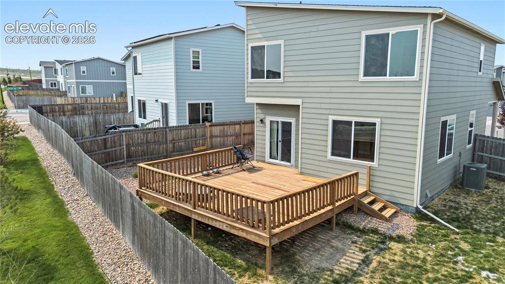Image 35 of 45: Rear view of home and backyard deck with stairs to the yard.