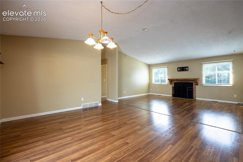 Image 10 of 26: Wood-finish flooring throughout, recessed lighting, and a fireplace with a 