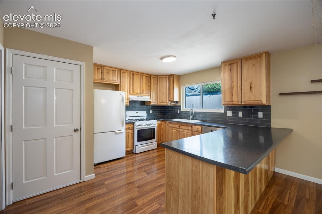 Image 11 of 26: Kitchen featuring wood-finish flooring, natural wood cabinetry, dark subway