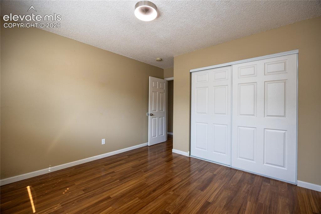 Image 17 of 26: Wood-finish flooring with a ceiling-mounted light fixture, and white slidin
