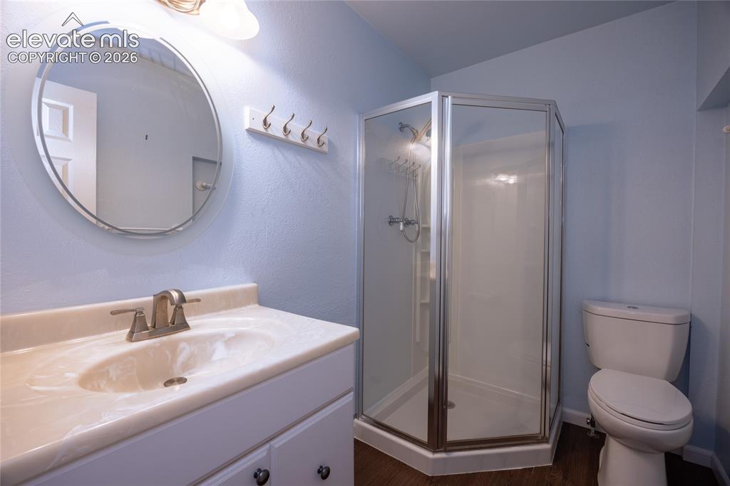 Image 18 of 26: White vanity with integrated sink, brushed nickel faucet, and round mirror