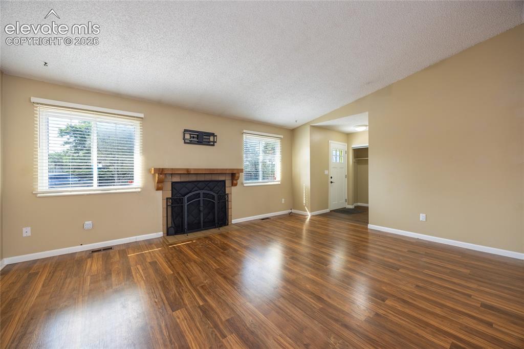 Image 7 of 26: Wood-finish flooring throughout, framed windows with blinds, and a fireplac