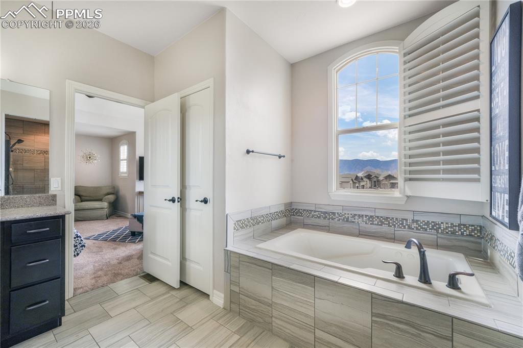 Image 26 of 50: Upper level primary bedroom with sitting area, 5 piece bath with dual vanit