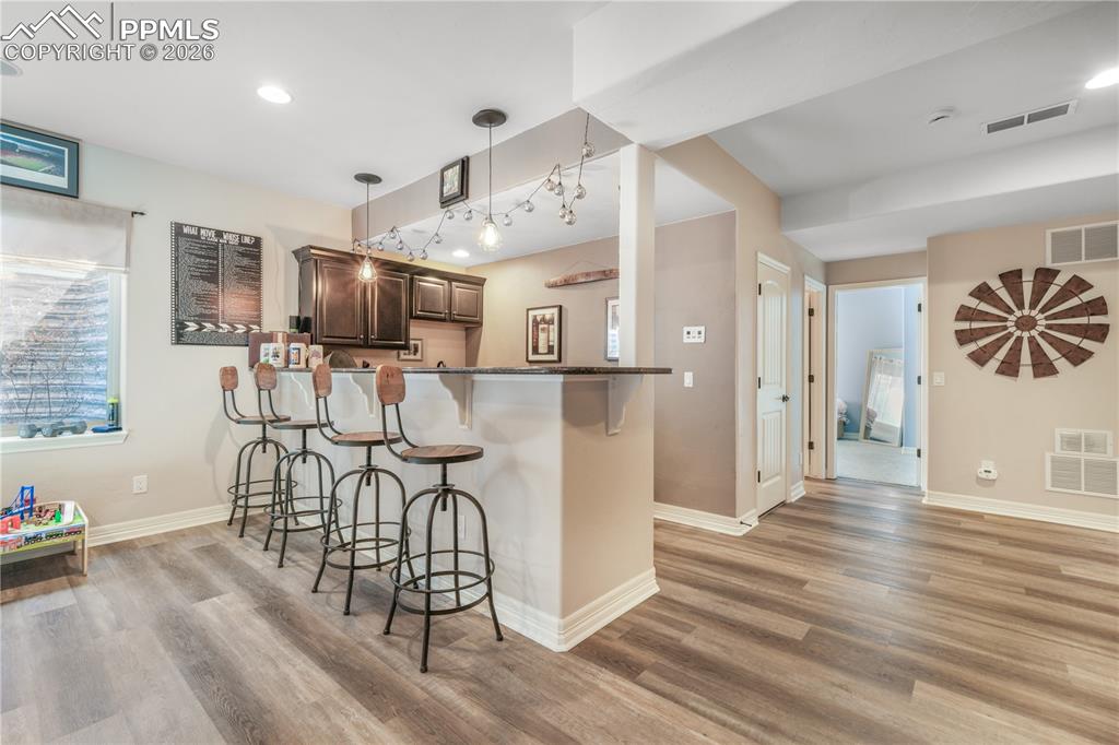 Image 40 of 50: Basement level family room with full wet bar and LVP flooring