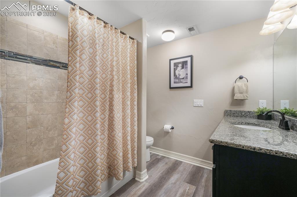 Image 43 of 50: Basement level family room with full wet bar and LVP flooring