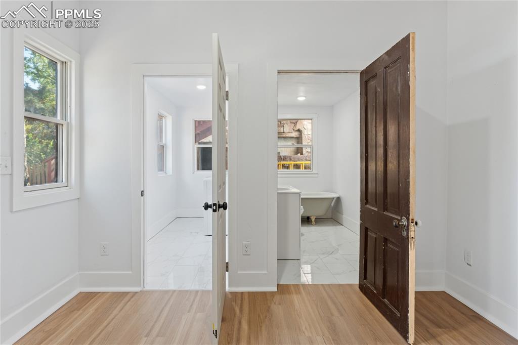 Image 10 of 49: Main-level laundry, bath with clawfoot tub and shower attachment
