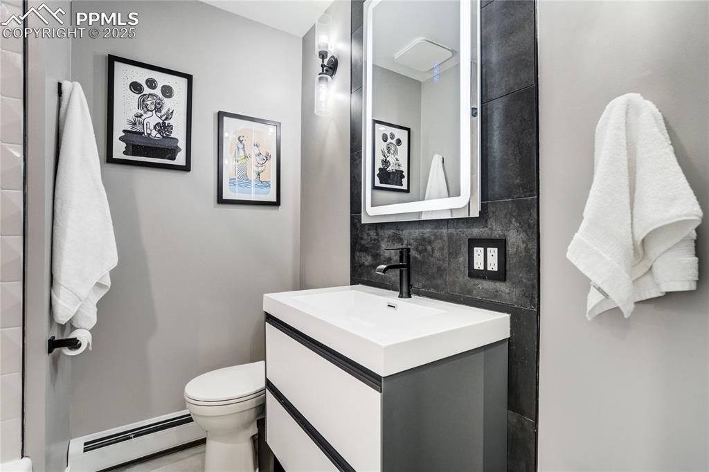 Image 33 of 46: Hallway bathroom with lighted mirror and custom tiling
