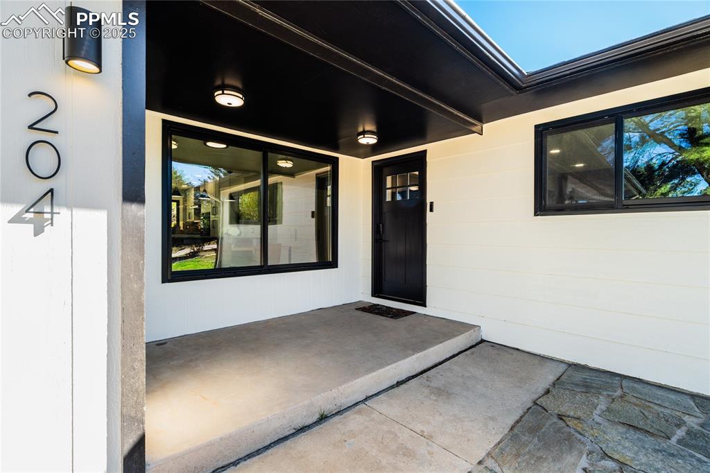Image 4 of 46: Covered front porch with open paver patio