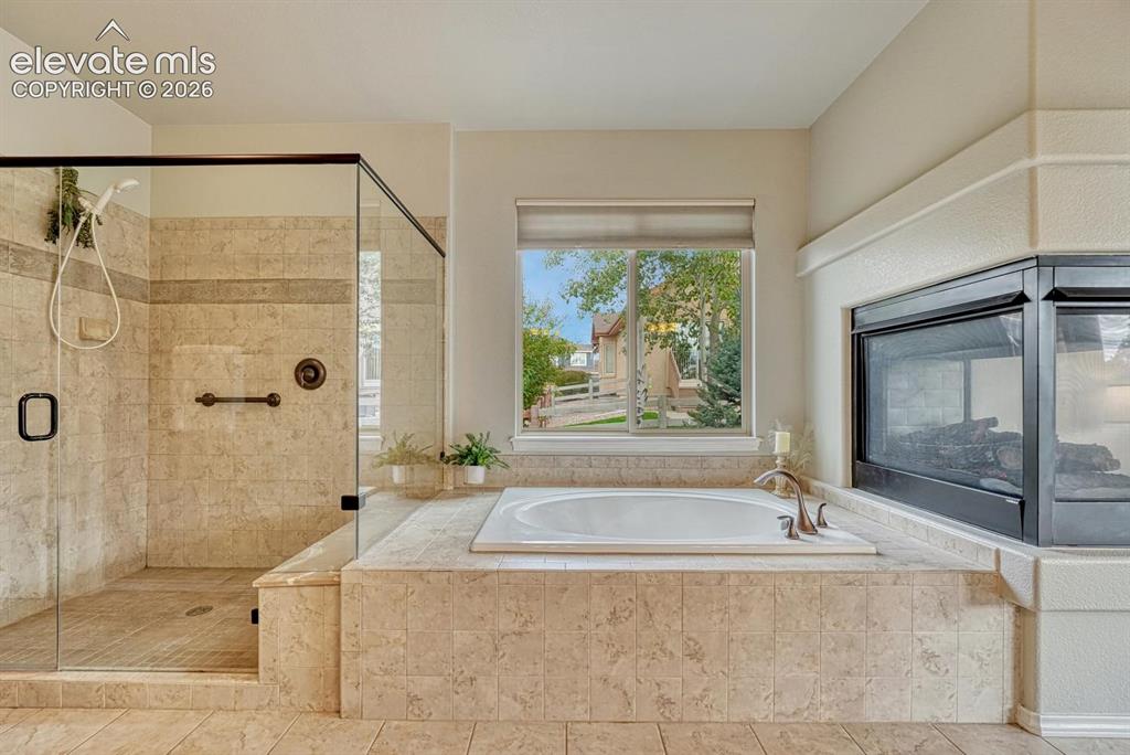Image 10 of 50: Luxurious 5-piece Primary Bathroom with 3-sided fireplace, soaking tub, and