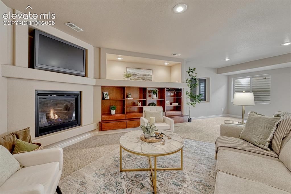 Image 11 of 50: Basement Family Room with neutral carpet, gas fireplace, built-ins, and TV