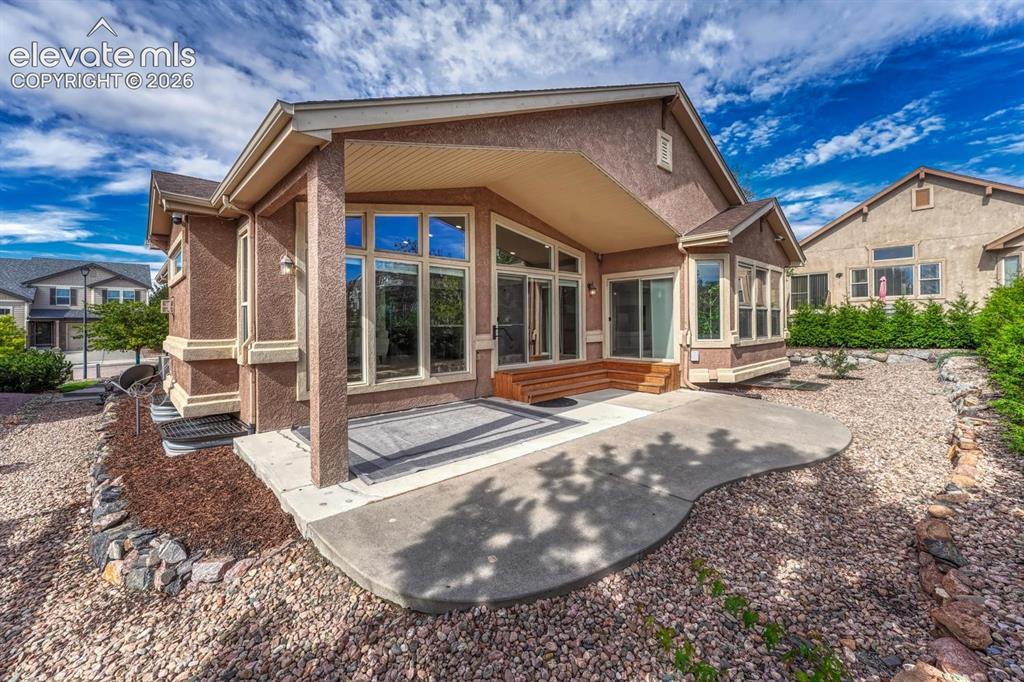 Image 13 of 50: Low maintenance xeriscaped backyard yard with partially covered patio and m