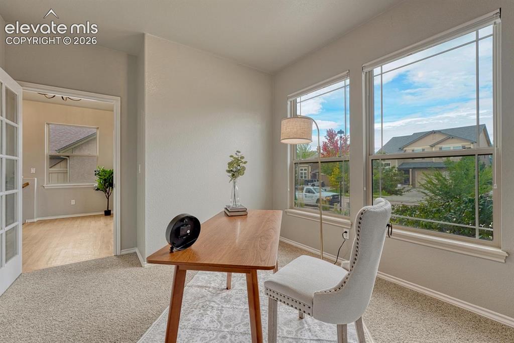 Image 19 of 50: French doors lead into the front office with neutral carpet and front yard
