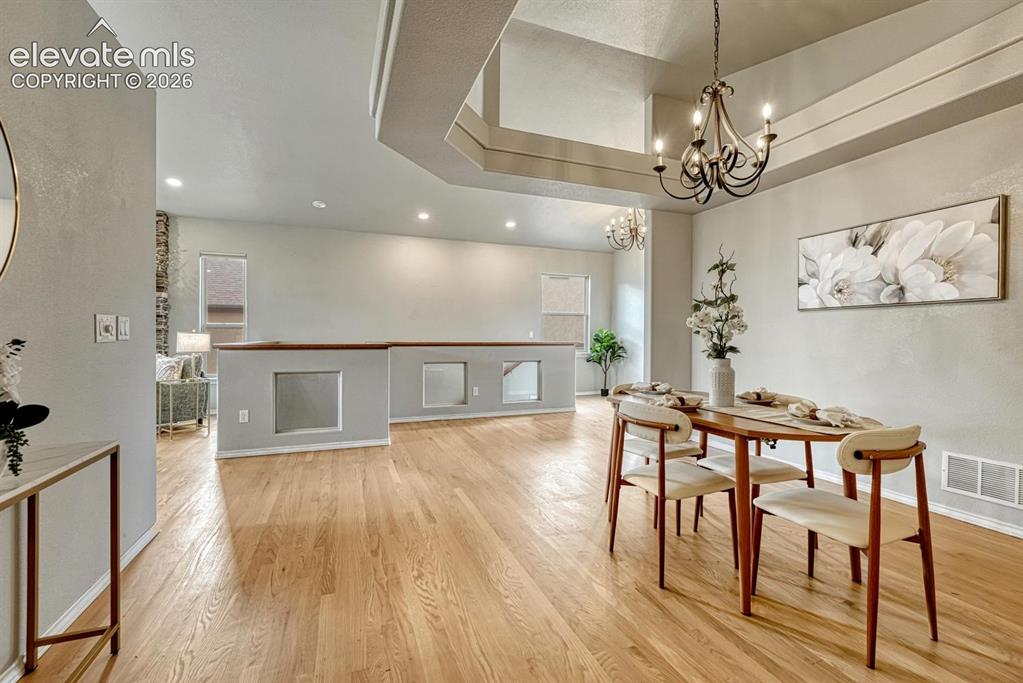 Image 25 of 50: The formal Dining Room features wood flooring and a tray ceiling with attra