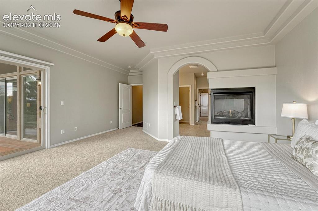 Image 28 of 50: The Primary Bedroom boasts a 3-sided gas fireplace and arched entry into th