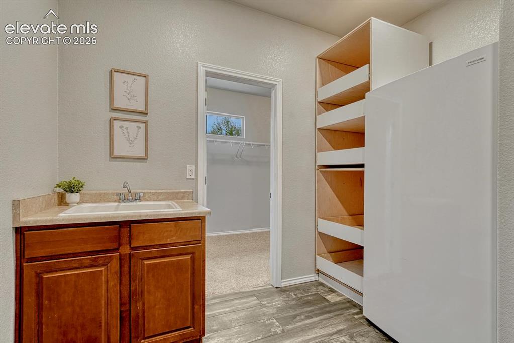 Image 31 of 50: The main level Laundry Room features wood look tile flooring, a utility sin