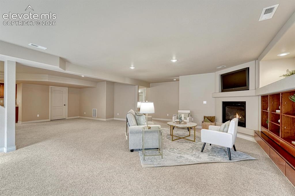 Image 35 of 50: Large Basement Family Room with neutral carpet, gas fireplace, TV niche, an