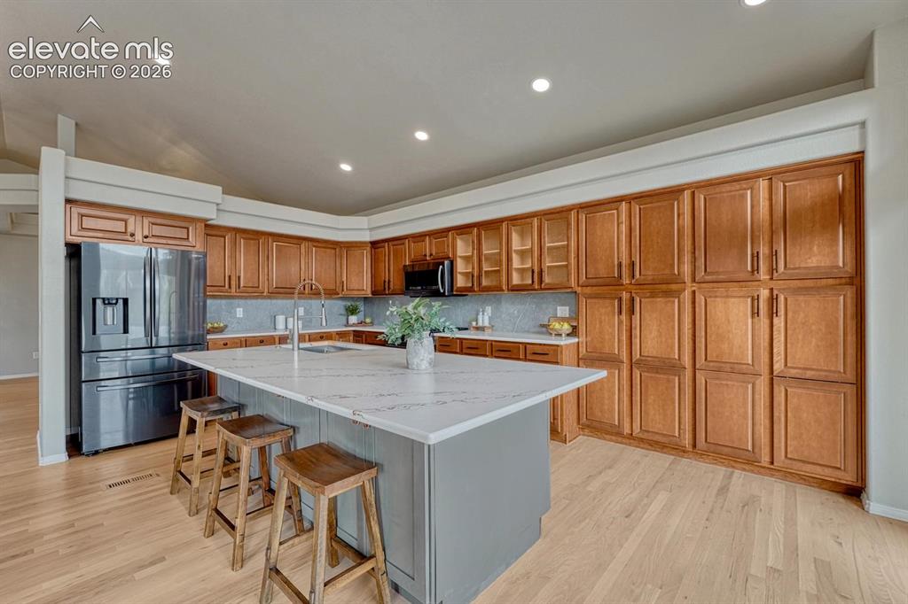 Image 4 of 50: Beautiful large island with quartz countertop, breakfast bar, and wall of w