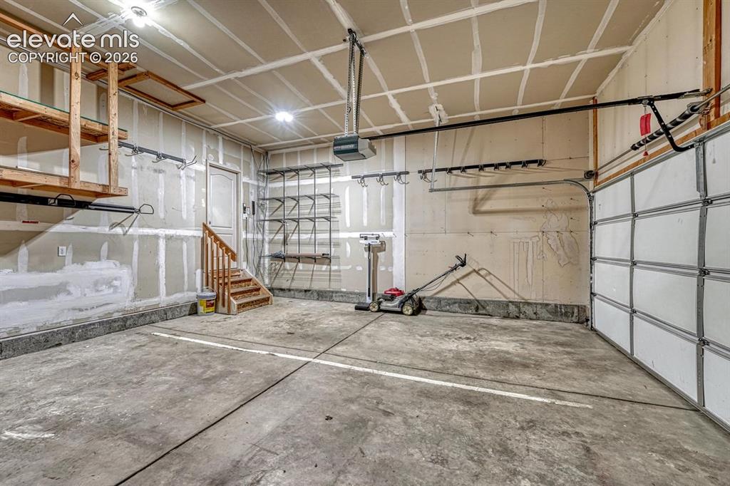 Image 42 of 50: 3-car attached garage with mounted tool rack and custom storage that stays.