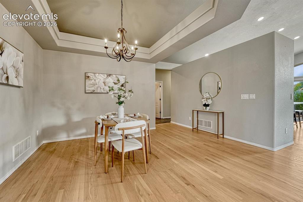 Image 8 of 50: Formal Dining Area, perfect for entertaining with wood floor, tray ceiling,
