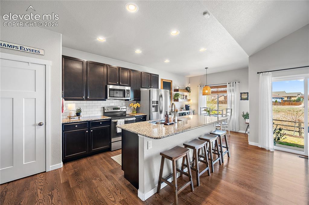 Image 6 of 44: Kitchen is open and bright with dark wood cabinetry, large island/breakfast