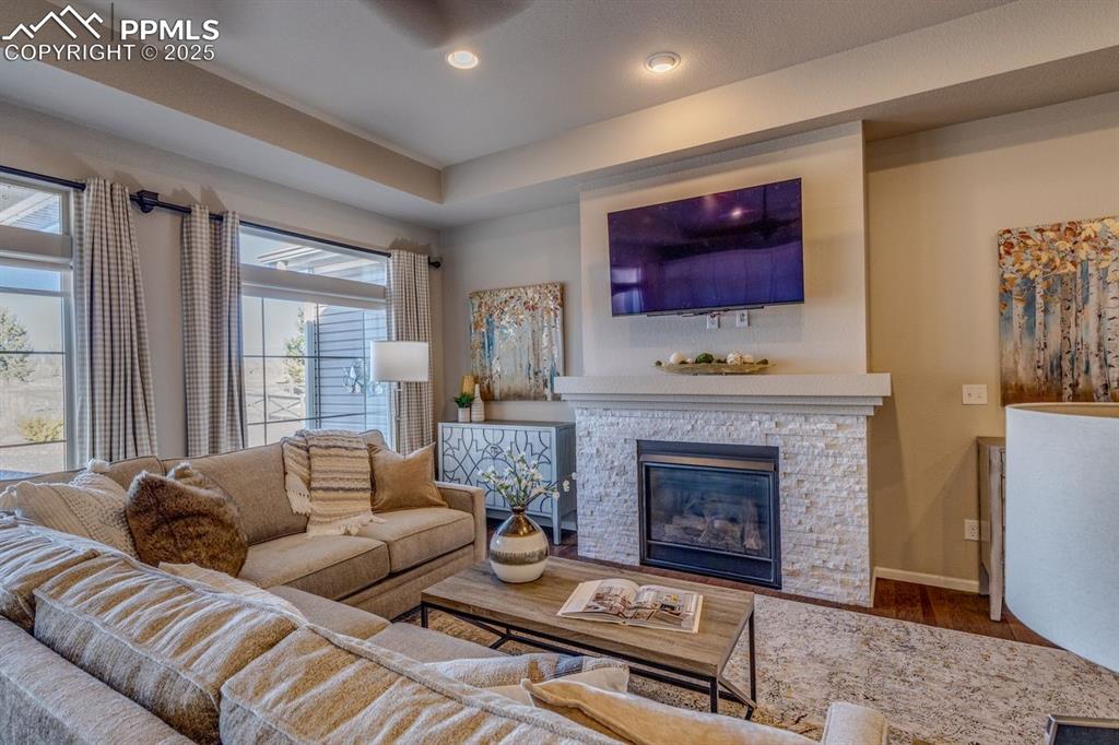 Image 19 of 50: Living area with a stone fireplace, wood finished floors, recessed lighting