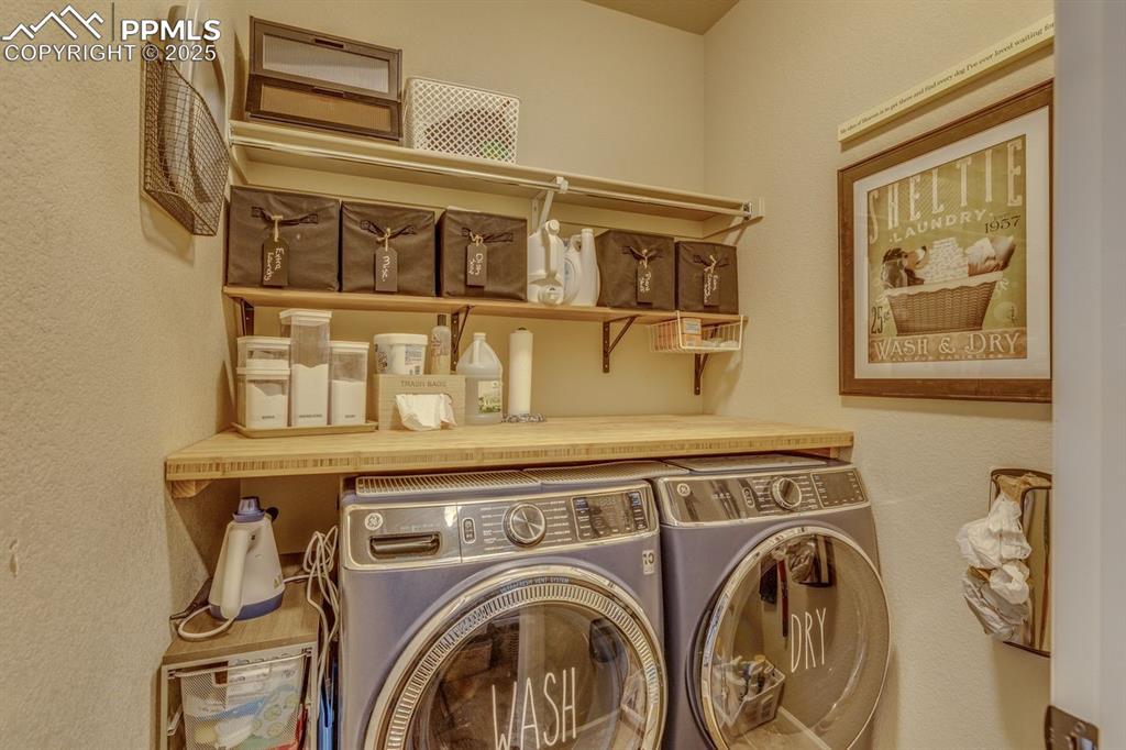 Image 26 of 50: Laundry area with a textured wall and washing machine and clothes dryer