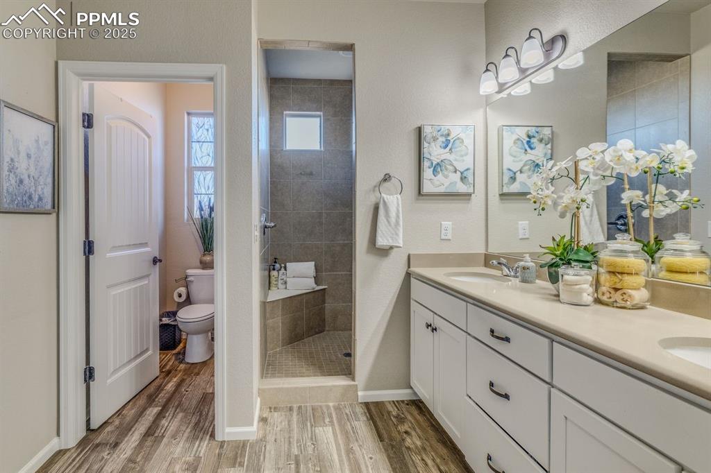 Image 29 of 50: Full bathroom featuring double vanity, a tile shower, and light wood finish